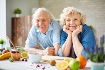 happy senior man and woman looking at camera in the kitchen