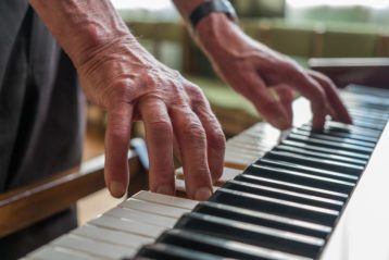 A senior man with a worker's hands playing the piano. close up