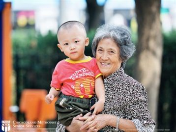 An Asian grandmother holding up her grandchild