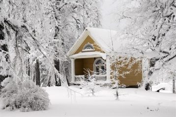 A small house in a forest covered in fresh white snow