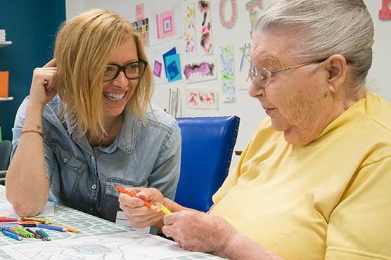 two women smiling while in an arts and crafts room