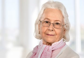 senior adult woman with glasses and a cute pink scarf