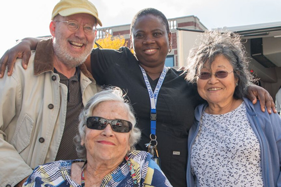A group of seniors and a caregiver pose for a photo while on an excursion around town