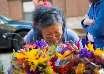 A woman looks through the flowers at the Andersonville Farmer's Market