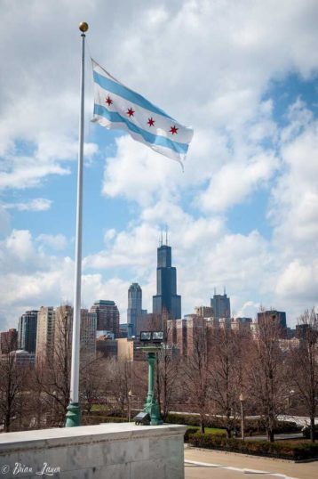 Flag of Chicago flying high with the city itself in the backdrop