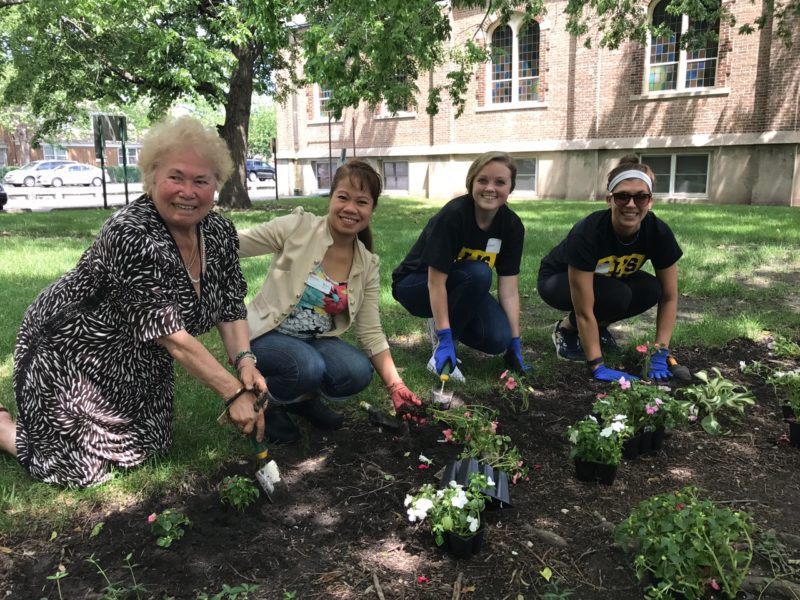 volunteers help plant flowers just outside a Chicago Methodist Senior Services operated building