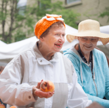 Two women that part of an advanced memory care community, visit a local farmers market