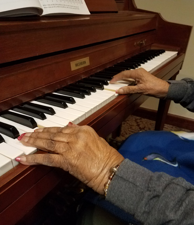 A pair of hands plays on a Washburn piano as part of a music therapy program