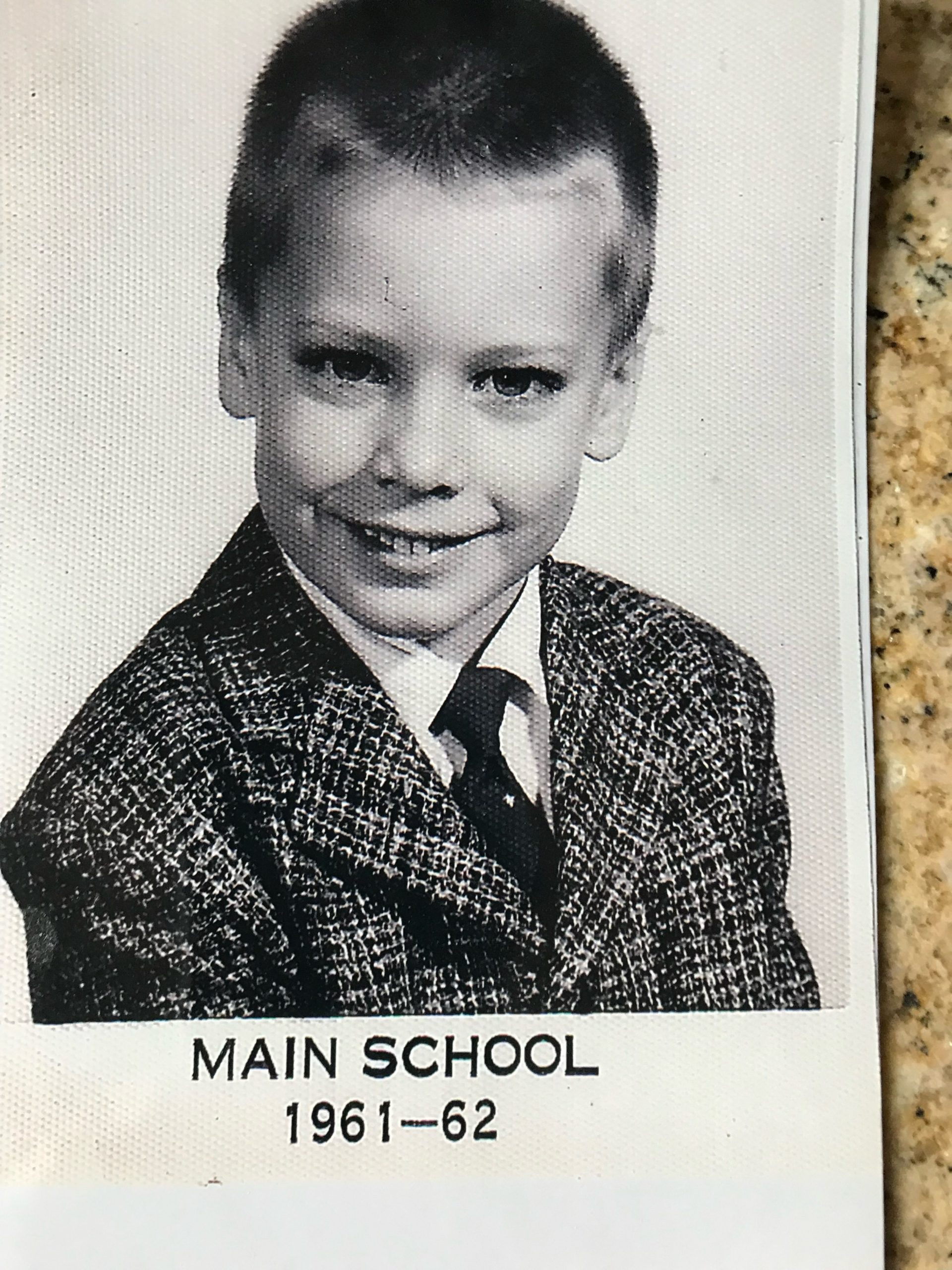 A black and white yearbook photo of a young boy in a plaid suit. Below the photo reads the caption: "MAIN SCHOOL 1961-62"